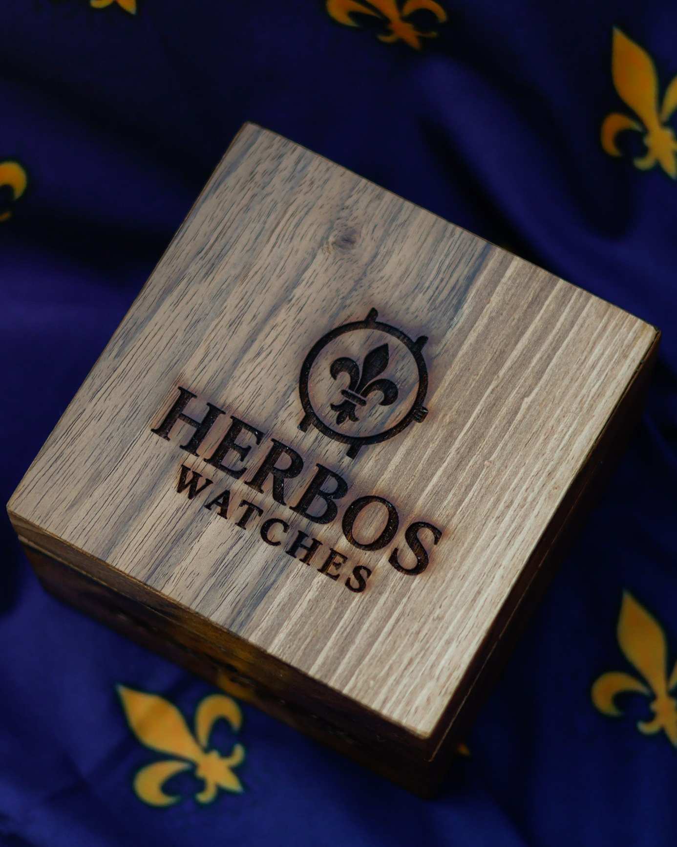 Walnut wood box with the engraved Herbos Watches logo on a lily fabric